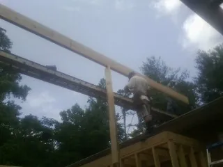 Carpenter setting a ridge beam over a new addition frame — Ice Dam Removal by Roofing Brothers in Pine Hall