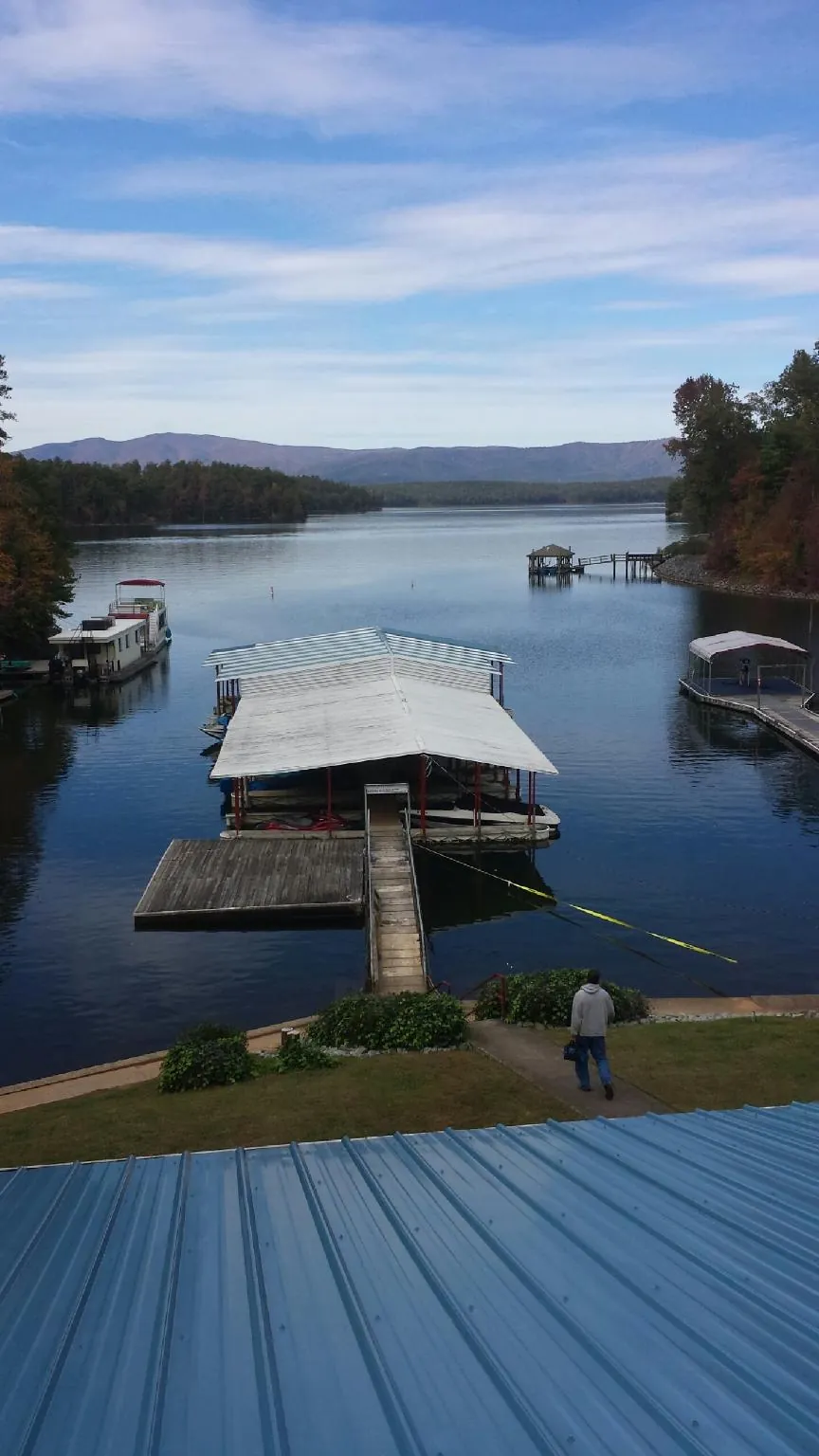 View across a lake from a newly installed blue metal roof in Pine Hall