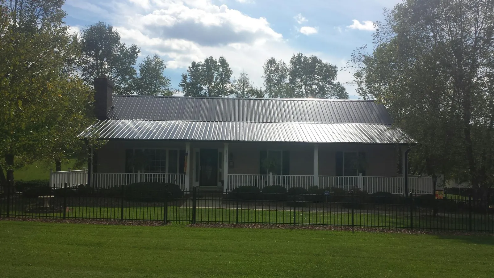 Gray metal roof on a brick ranch with a full width front porch — Gutter Guard Installation work by our crew in Pine Hall