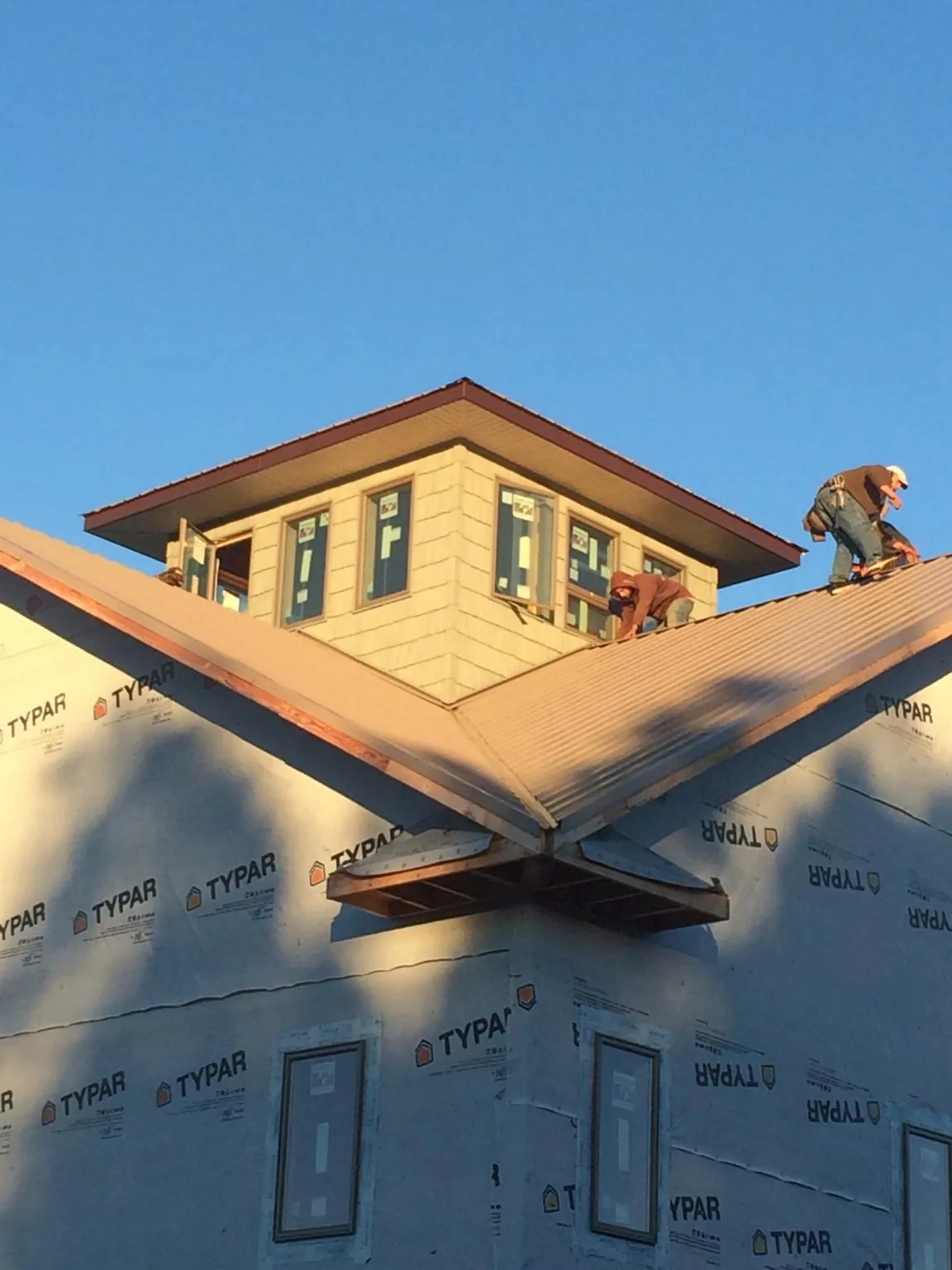 Roofers working around a rooftop cupola on a new metal roof at sunset — Roof Waterproofing in Pine Hall by Roofing Brothers